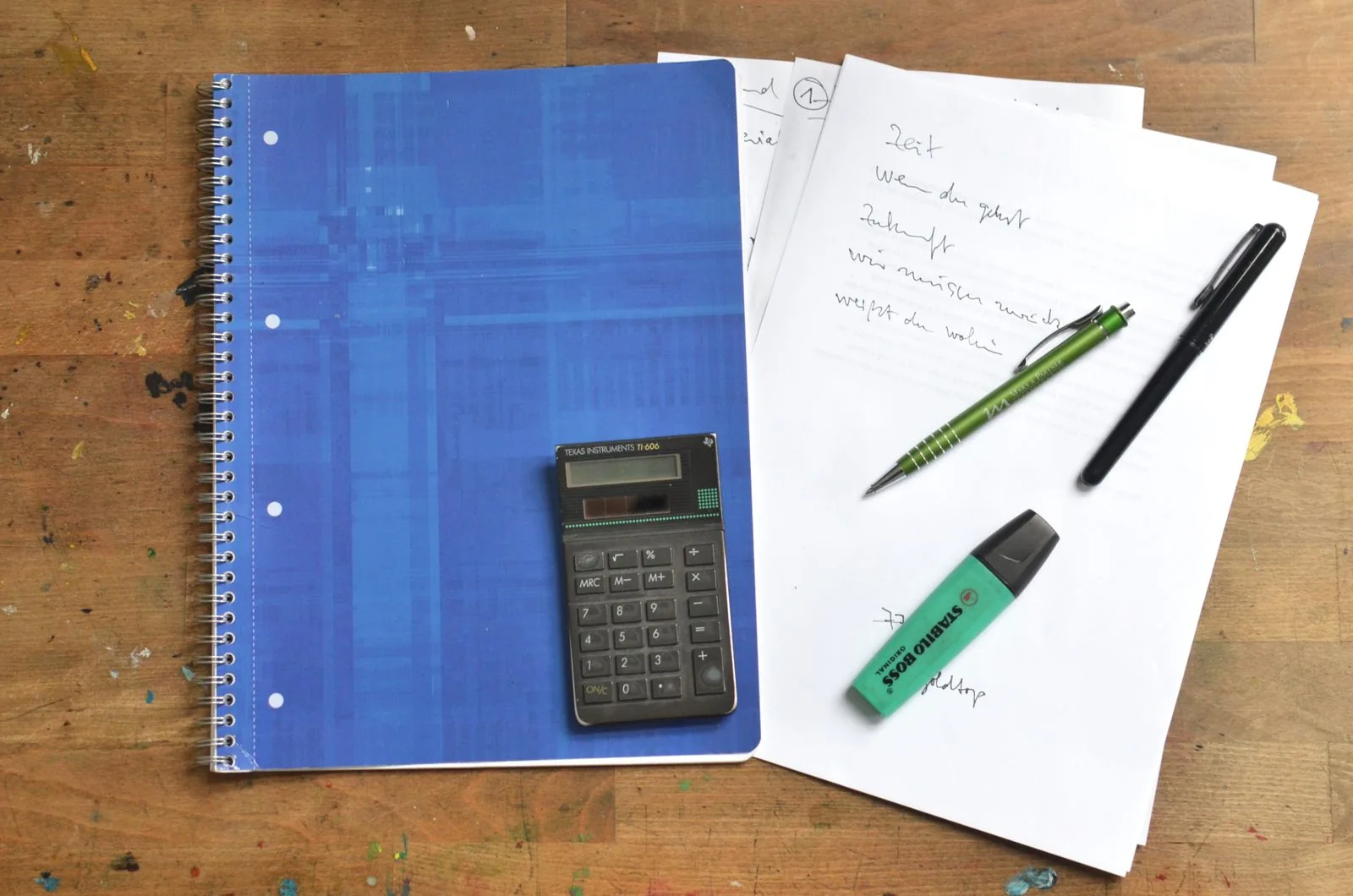 Notebook, pens and stationery on a wooden desk
